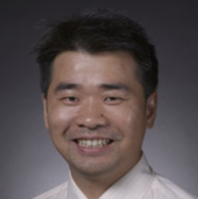 man with dark hair wearing a white collared shirt smiling